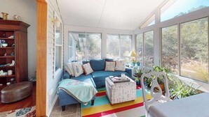 Una habitación iluminada por el sol con un sofá azul, una mesita y una silla.