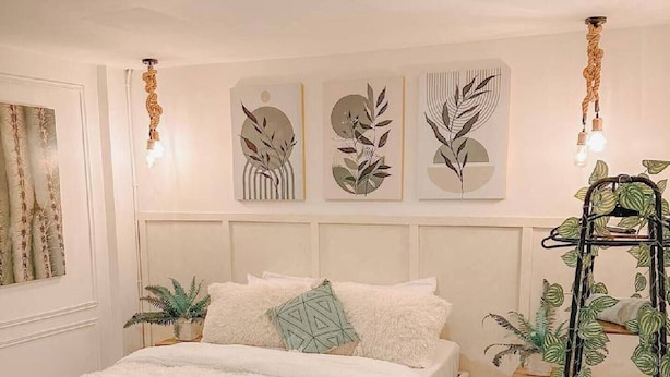 Ein Schlafzimmer mit einem Bett, einem Pflanzenregal und Wandkunst.