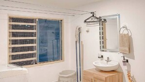 Ein Badezimmer mit einem weißen Waschbecken, einem Holzkorpus und einem Fenster mit Jalousien.