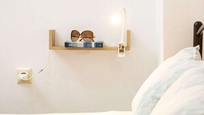 Ein Nachttisch mit einer Sonnenbrille, einer Lampe und einer Steckdose.