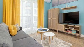 A living room with a sofa, a coffee table, a TV, and a bookshelf. - Cozy Apartment | Air Conditioning | Balcony | Parking. (Ustronie Morskie)
