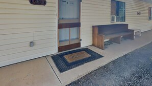 Eine Lodge mit Holztür, einer Bank davor und einer Fußmatte.
