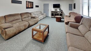Ein Wohnzimmer mit zwei Sofas, einem Couchtisch, einem Fernseher und einem Bücherregal.