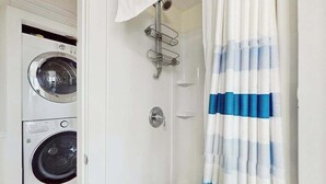 Una sala amb bugaderia que disposa de dues rentadores, un teló de dutxa i un suport per a tovalloles.