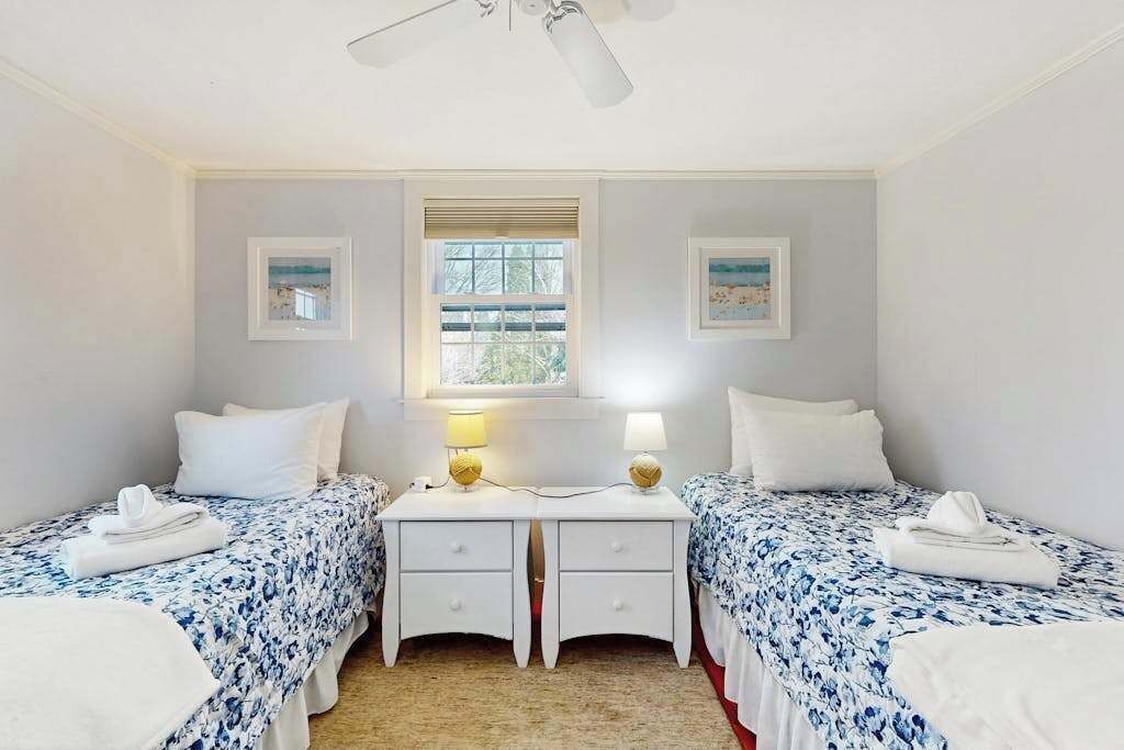 Ein Doppelzimmer mit zwei Betten, einem Fenster und einem Deckenventilator.