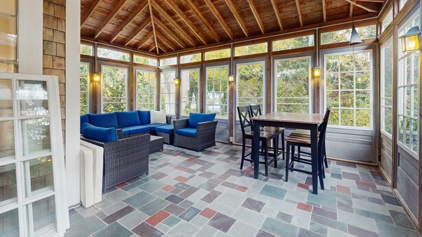 A covered patio with a wooden ceiling, large windows, and a tiled floor. - Dog-friendly historic home with yard, games, grill, children's items, W/D, & AC (Barnstable)
