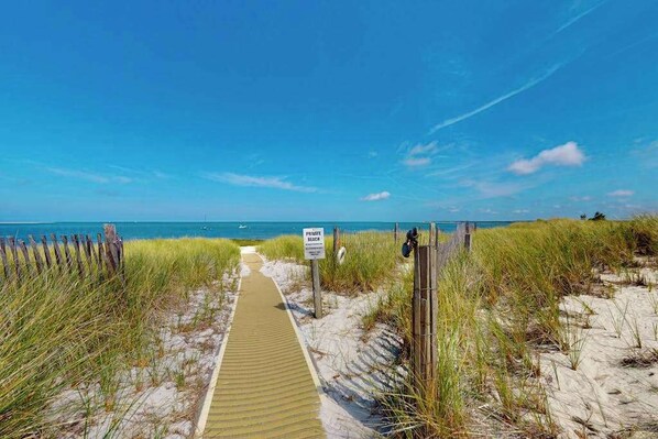 A beach path leading to the ocean with a sign indicating a public beach.