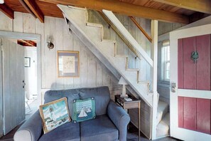 A staircase with wooden steps and a white handrail, a gray sofa with two decorative pillows, and a small table with a lamp.