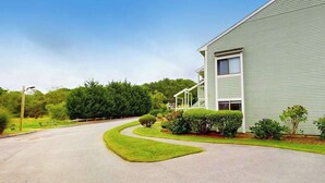 A two-story building with a green exterior, a curved driveway, and well-maintained landscaping.