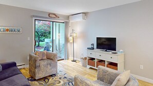 A living room with a sofa, two armchairs, a flat-screen TV, a white cabinet, and a patterned rug.