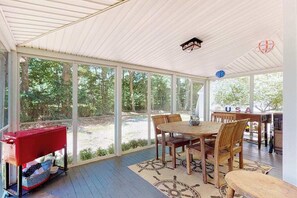 A covered patio with a dining table, chairs, and a grill. - Welcoming home on Main St. with screened porch & large yard - 1 dog OK (Cotuit)
