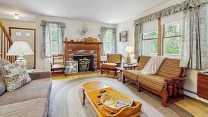 Una sala de estar acogedora con chimenea, asientos cómodos y un ventilador.