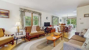 Una sala de estar con sofá, sillones, una mesa de centro, televisor y un comedor con sillas y mesa.