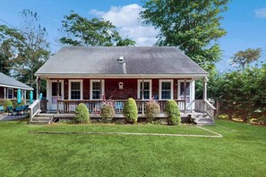 Ein zweigeschossiges Haus mit Veranda, Vordergarten und kleinem Garten.