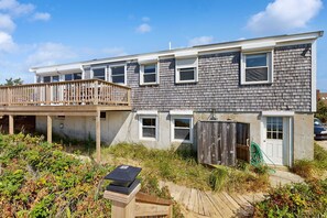 A two-story residential building with a balcony, a wooden deck, and a garden area.