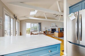 A spacious kitchen with a large island, a dining area with a view, and a modern living space with a fireplace.