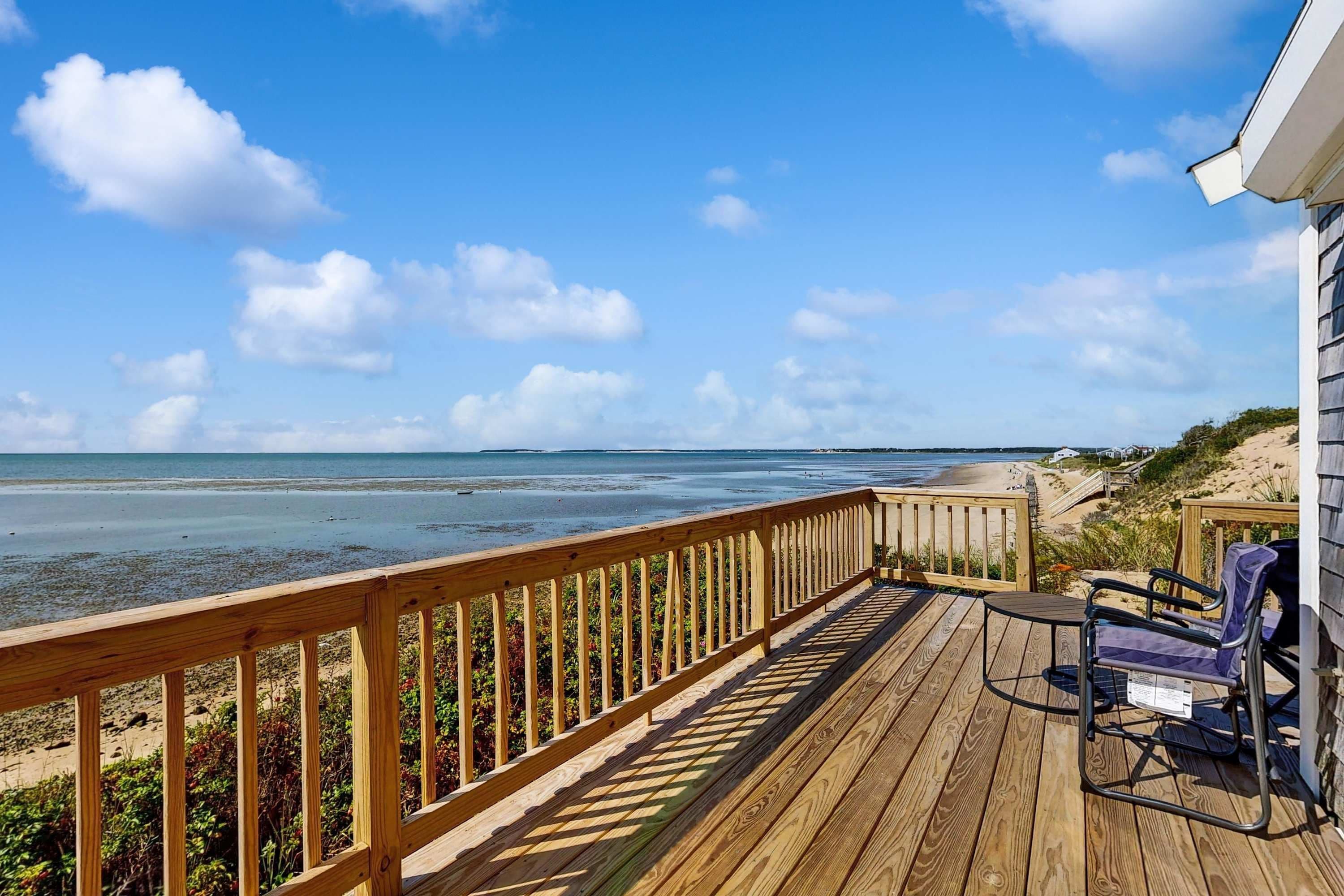A wooden deck with a view of the beach and ocean.