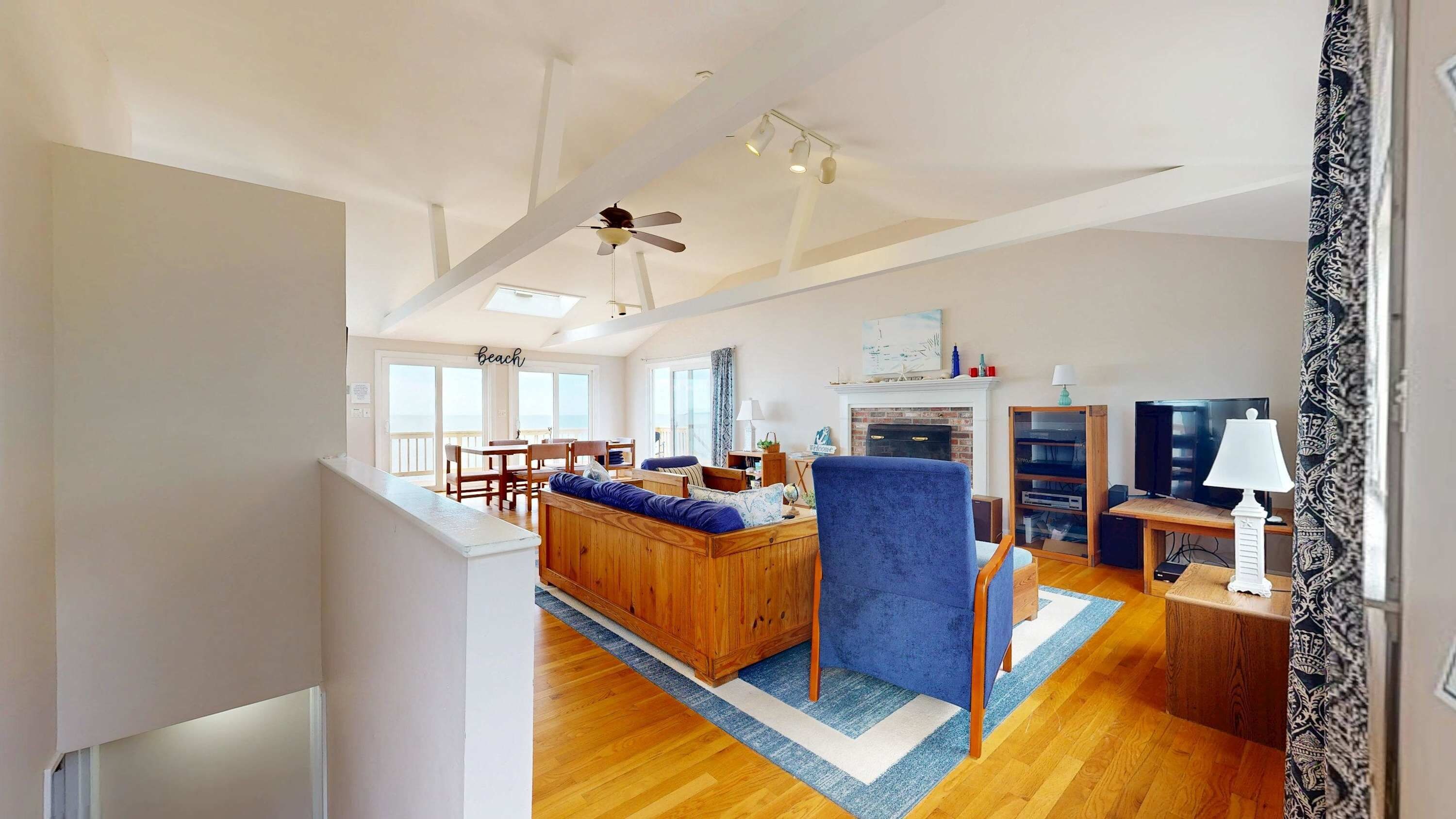 A spacious living room with a wooden sofa, a blue armchair, and a fireplace.