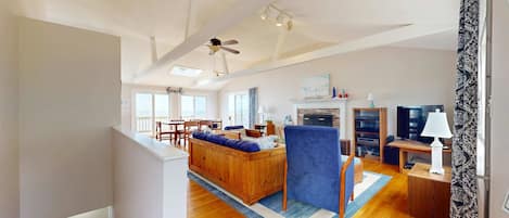 A spacious living room with a wooden sofa, a blue armchair, and a fireplace.