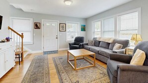 Una sala de estar con sofá, sillón, mesa de centro y una escalera.