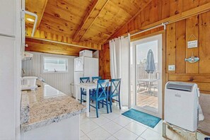 A wooden interior with a kitchen, dining area, and a sliding glass door leading to an outdoor patio.