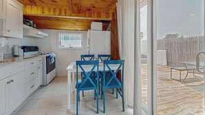 A wooden interior with a kitchen, dining area, and sliding glass door to an outdoor deck. - Charming cottage with private W/D, wifi + minutes to beach (Dennis)