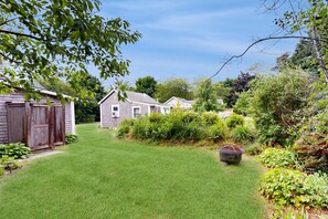 A residential property with a well-maintained lawn, a wooden shed, and a variety of shrubs and plants. - Cottage near Cape Cod National Seashore with firepit, grill, kitchenette, & AC (Eastham)
