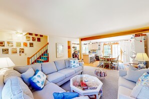 A living room with a sofa, coffee table, and a staircase leading to a kitchen area.