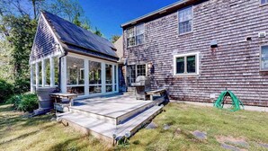 Une maison en bois dotée d’un patio couvert et d’un garage séparé.