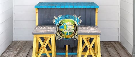 A wooden surfboard with signatures, a blue and yellow bench with a logo, and a clock on the wall.