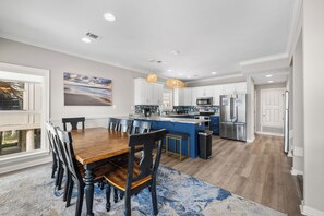 A modern kitchen with a central island, white cabinetry, and stainless steel appliances. - Gulf Front | 6 Bedrooms | Spacious West Beach Retreat (Gulf Shores)