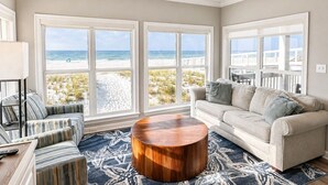 Ein Wohnzimmer mit Blick auf den Strand, einem runden Couchtisch und einem Sofa.
