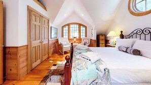 Een slaapkamer met een groot bed, een houten garderobe en een raam met uitzicht.