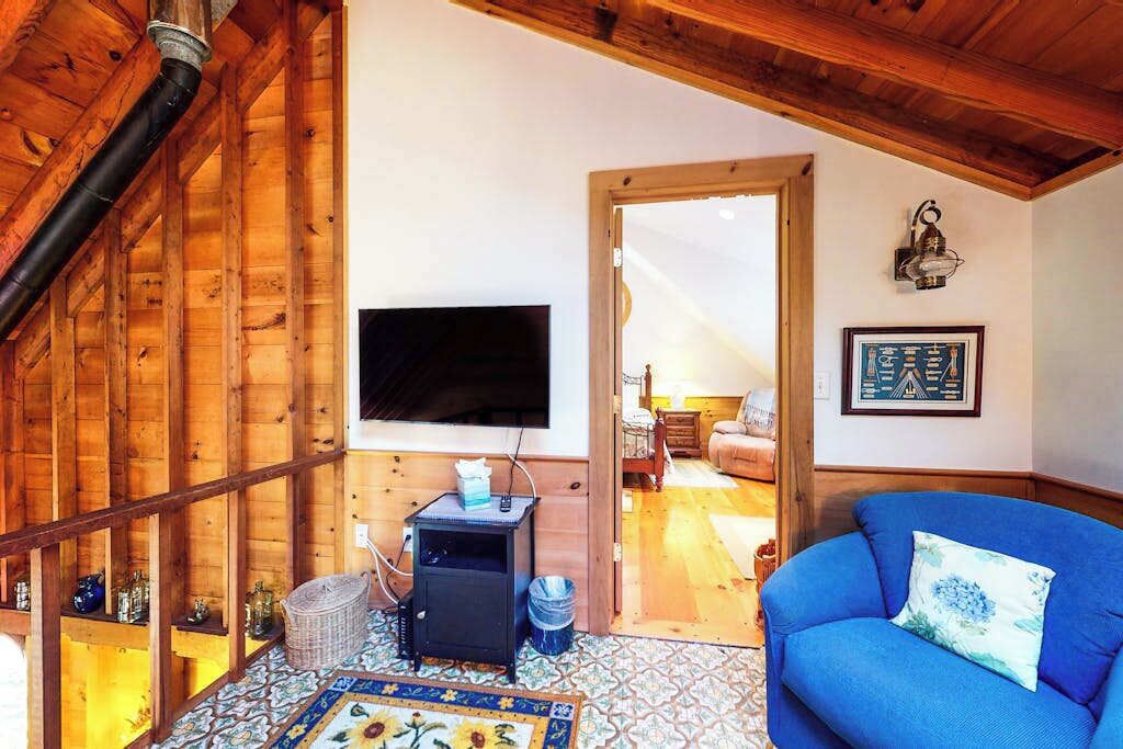 A wooden interior with a television, a blue sofa, and a patterned rug.