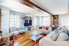 A living room with a television, sofas, a coffee table, and a fireplace. - Historic charmer on the water with a firepit, kayaks, bikes, & firepit (Eastham)