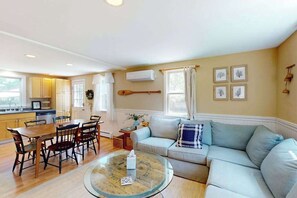 A living room with a sofa, a round coffee table, and a dining area with chairs and a table.