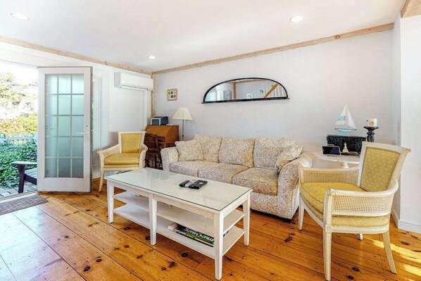 A cozy living room with a sofa, two chairs, a coffee table, and a side table with a lamp.