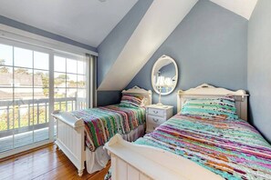 A bedroom with two beds, a large window, and a sloped ceiling.
