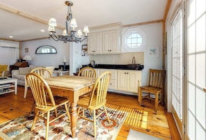 A cozy kitchen with wooden cabinets, a dining table with chairs, and a chandelier.