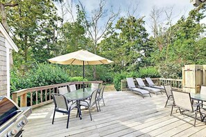 Eine Terrassenausstattung mit Tisch, Stühlen, einem Grill und Liegestühlen.