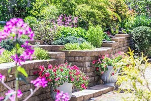 A garden with stone steps, potted plants, and various shrubs. - Beautiful Harwich home with large yard near Red River Beach & Main Street fun (Harwich)