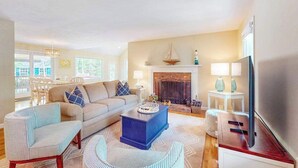 A living room with a sofa, chairs, a coffee table, a fireplace, and a television. - Peaceful beach retreat: private yard, close to beaches, Chatham & rail trail (Harwich)