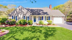 A single-story house with a front porch, a garage, and a well-maintained lawn. - Peaceful beach retreat: private yard, close to beaches, Chatham & rail trail (Harwich)