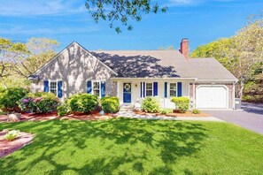 A single-story house with a front porch, a garage, and a well-maintained lawn. - Peaceful beach retreat: private yard, close to beaches, Chatham & rail trail (Harwich)