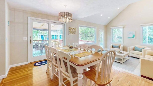 A spacious living area with a dining table, chairs, a sofa, and a ceiling light fixture. - Peaceful beach retreat: private yard, close to beaches, Chatham & rail trail (Harwich)