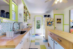 A kitchen with a tiled backsplash, a wooden countertop, and a refrigerator with magnets. - Lakefront Cottage with a Deck, Free WiFi, Gas Grill - Close to Ferries & Beaches (Oak Bluffs)