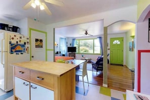 A compact kitchen with a wooden table, a refrigerator, and a dining area with chairs. - Lakefront Cottage with a Deck, Free WiFi, Gas Grill - Close to Ferries & Beaches (Oak Bluffs)