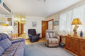 A living room with a sofa, two recliners, a lamp, and a cabinet with nautical decorations. - Cape Cod charmer with a large yard, deck, grill, beach gear, & central AC (Hyannis)