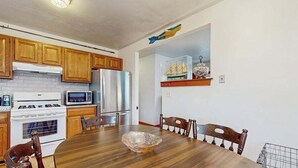 Eine Küche mit Holzausstattung, einem Edelstahl-Kühlschrank, einer Mikrowelle und einem Herd.