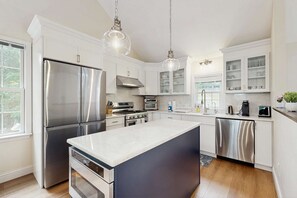 A modern kitchen with stainless steel appliances, white cabinetry, and pendant lighting. - Pond Treasure: Private beach, hot tub, sauna, play area & dog-friendly (Sandwich)